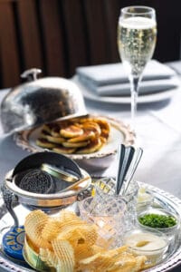 Elegant caviar platter served with potato chips, and a glass of champagne.