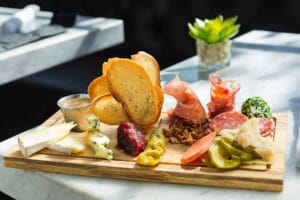 Charcuterie board with a variety of meats, cheeses, and accompaniments on a white marble table.