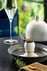 Exquisite dish featuring an egg filled with caviar, served in a modern setting.