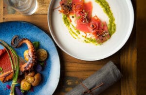 Savor grilled octopus and ahi tuna with garnishes on blue and white plates.