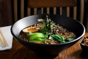 Hot soba noodles with egg and bok choy in a black bowl.