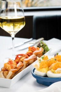 Close-up of lobster rolls and crispy shrimp deviled eggs served with white wine