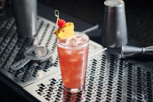 tropical-rum-punch-cocktail Tropical rum punch cocktail on ice, garnished with pineapple wedge and cherry.